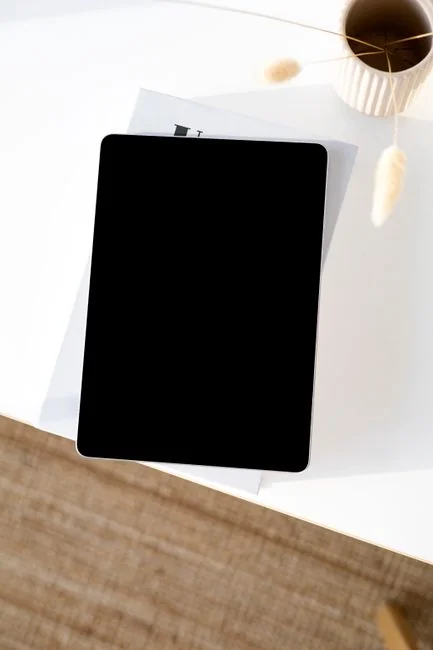 A photographer working at a creative setup with a laptop and Wacom tablet, focused on editing photos indoors.